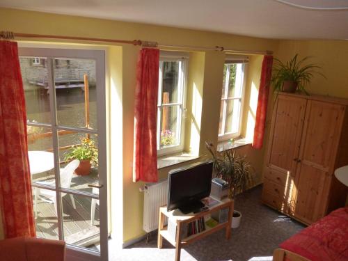 Una sala de estar con dos ventanas y un televisor. en Ferienwohnungen Am Breitstrom, en Erfurt