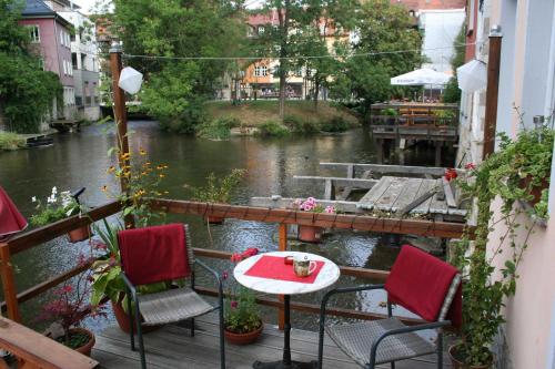 una mesa y sillas en un balcón con un río en Ferienwohnungen Am Breitstrom, en Erfurt