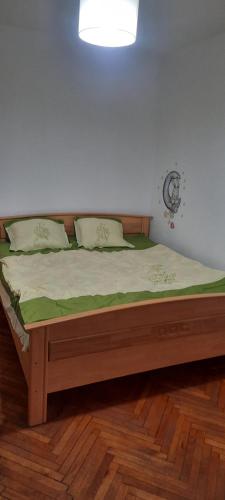 a bedroom with a wooden bed with green sheets at Apartament in Craiova