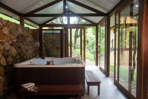 a bathroom with a tub in a stone wall at Pousada Terra Crua in Visconde De Maua