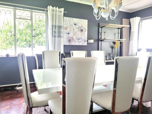 ein Esszimmer mit weißen Stühlen und einem Tisch in der Unterkunft City Gate Two in Pietermaritzburg
