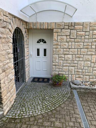 a stone building with a white door and a stone wall at Ferienwohnung Am Luisenpark in Erfurt