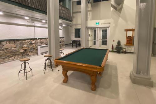 a pool table in a large room with stools at Snow Ghost Inn 326 in Big White