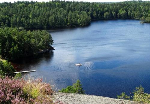 a small boat in a large lake with trees at Flybo Sjöaborg, Smaland, South Sweden in Åseda