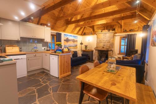 a kitchen and living room with a wooden ceiling at Tigh Lachie at Mary's Thatched Cottages, Elgol, Isle of Skye in Elgol
