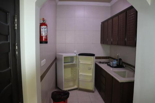 a small kitchen with a refrigerator and a sink at Yanbu Inn Residential Suites in Yanbu