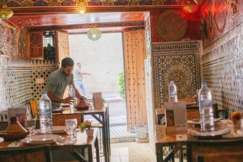 a man standing at a table in a restaurant at Riad Fes Hayat in Fez
