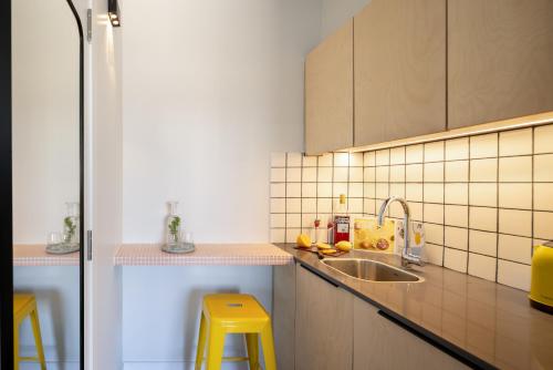 eine Küche mit einem Waschbecken und zwei gelben Hockern in der Unterkunft Savanna Dizengoff - Smart Hotel by Loginn Tel Aviv in Tel Aviv