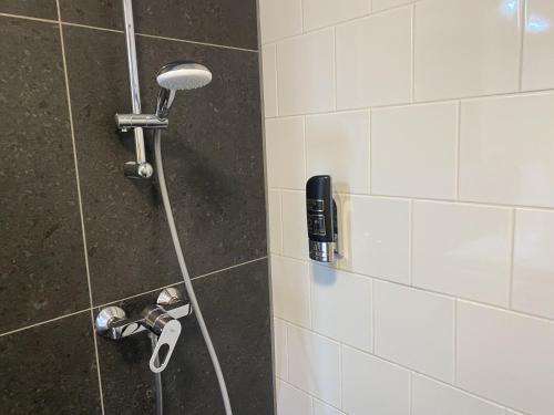 a shower with a hose attached to a tile wall at Apartmány Vodohospodár in Mýto pod Ďumbierom