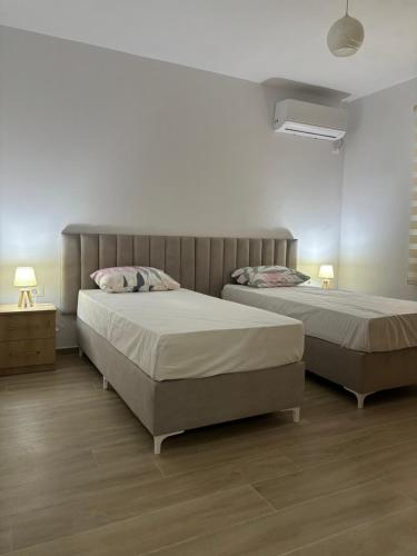 2 Betten in einem Schlafzimmer mit 2 Tischen und 2 Lampen in der Unterkunft Kevi ‘s place in Tirana