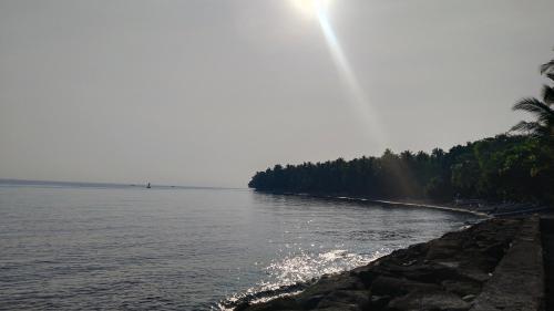 a beach with the sun shining on the water at Les Cantik Homestay in Tejakula