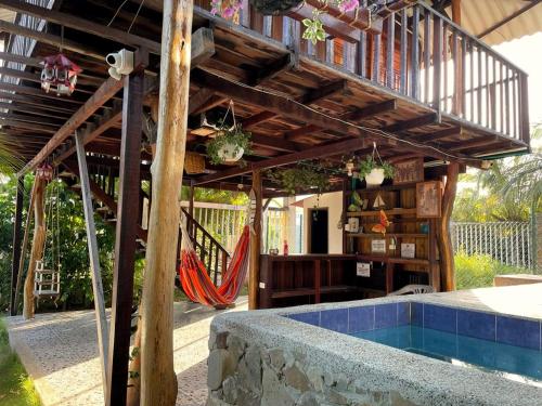 a wooden deck with a hammock and a swimming pool at Cabaña Caminito- Cerca al mar al lado de Turipaná, 7 a 12 personas in Carretal