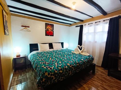 a bedroom with a bed with a green comforter at Wayras Hostal in Ollantaytambo