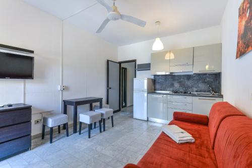 a living room with a red couch and a kitchen at Residence Le Acacie in Capoliveri