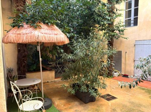 une terrasse avec une table, un parasol et un arbre dans l'établissement Appart Aix sauna jacuzzi balneo spa privatifs hyper centre historique cour intérieur, à Aix-en-Provence