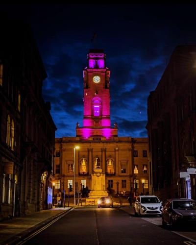 un edificio con una torre dell'orologio con luci viola di The Indulging Basement a Barnsley