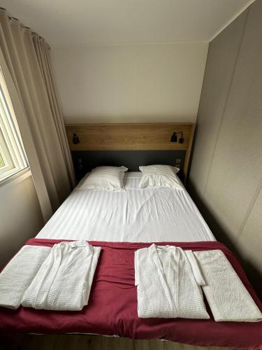 a bed with two white towels on top of it at Camping du Château Vert in Hondainville