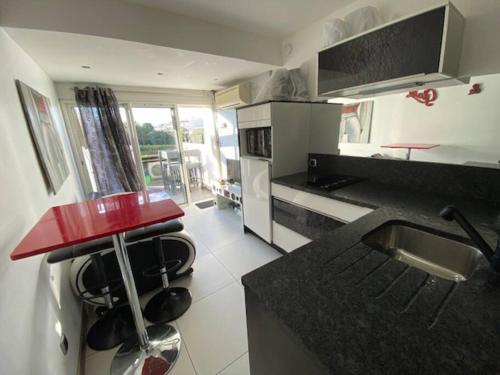 une cuisine avec un comptoir et un comptoir rouge dans l'établissement Studio 7, Port Nature 1 au village naturiste, au Cap d'Agde