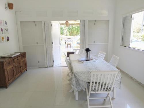 uma sala de jantar branca com uma mesa e cadeiras brancas em Villa Rossella em Morro de São Paulo