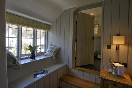 een badkamer met een spiegel, een raam en een wastafel bij Ring of Bells in North Bovey