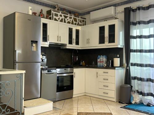 a kitchen with white cabinets and a stainless steel refrigerator at Vikis Dream Views in Skala Mistegnon
