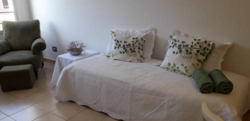 un letto bianco con cuscini e una sedia in una stanza di Espacio Aristobulo a Comodoro Rivadavia