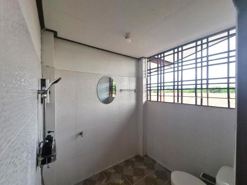a bathroom with a window and a toilet and a mirror at Ha Me Garden ฮามีการ์เด้น โฮมสเตย์ฝาง in Fang