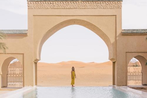 a woman standing in front of an arch in the desert at Sahara pearl Hotel in Merzouga