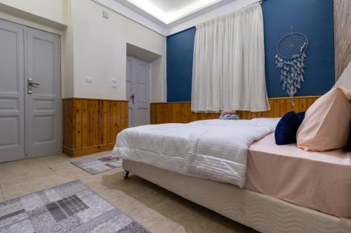 een slaapkamer met een bed en een blauwe muur bij Villa Khufu Pyramids Inn in Caïro