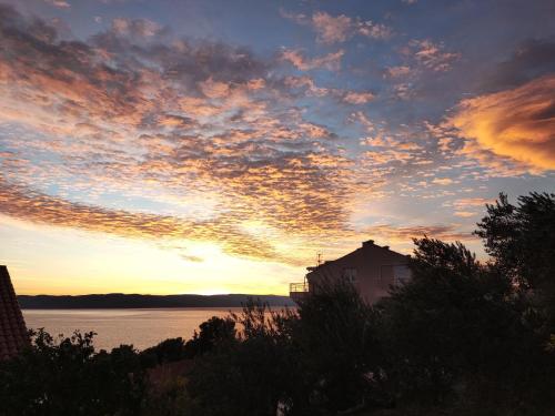 a sunset over the water with a house in the foreground at Apartments Mare in Brela