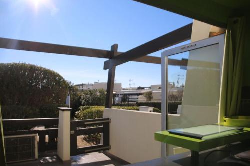 d'un balcon avec une table verte et une fenêtre. dans l'établissement Studio 6, Port Nature 1 au village naturiste, au Cap d'Agde