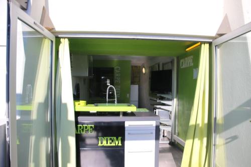 - une cuisine avec un évier et un mur vert dans l'établissement Studio 6, Port Nature 1 au village naturiste, au Cap d'Agde