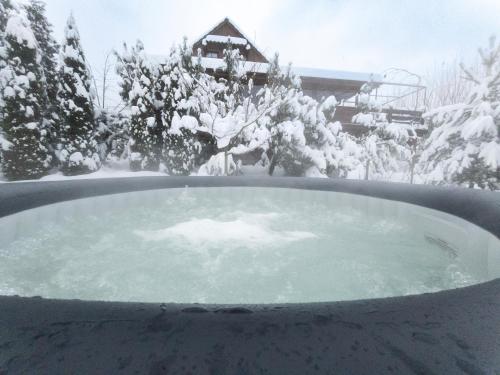 Sablówka的住宿－Górski Azyl w Soblówce，房屋前的雪覆盖的热水浴池