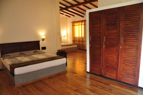 a bedroom with a bed and a large wooden closet at Asantha Guest House in Unawatuna