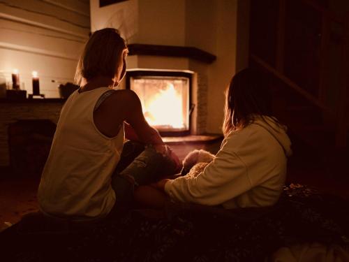 two women sitting on a couch in front of a fireplace at Górski Azyl w Soblówce in Sablówka
