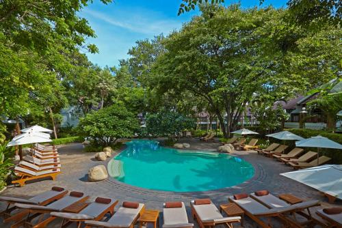 a swimming pool with chairs and umbrellas at Woodlands Hotel and Resort Pattaya in North Pattaya
