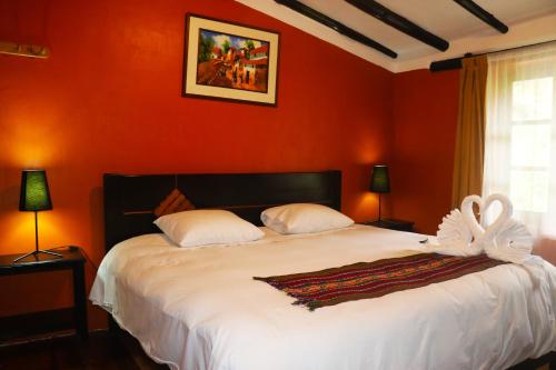 a bedroom with a large bed with red walls at Wayras Hostal in Ollantaytambo
