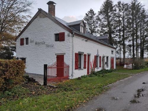 an old white house with red shutters on a street at Les Arpents Verts 52 