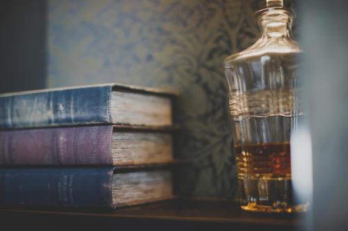 a bottle of whiskey next to a stack of books at Everything Retreat in Mellor