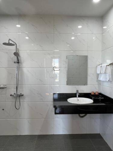a white bathroom with a shower and a sink at Đoàn Gia Luxury House in Pleiku