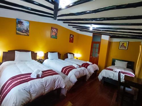 two beds in a room with yellow walls at Wayras Hostal in Ollantaytambo