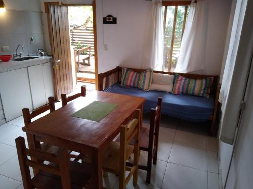 cocina y comedor con mesa y sofá en cabañas del bosque en Pinamar