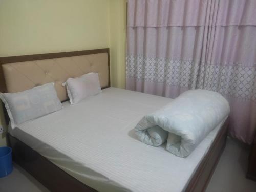 - un petit lit avec des draps et des oreillers blancs dans l'établissement Hotel aradhya, à Rummindei