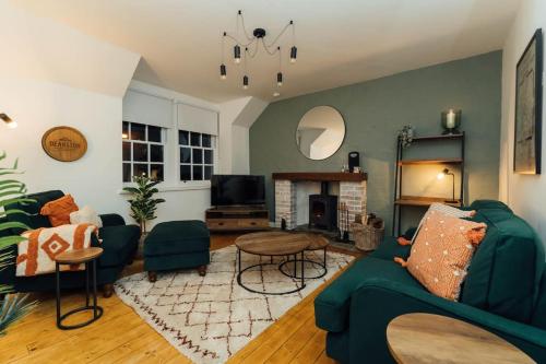 a living room with a green couch and a fireplace at The Old Deanston Workers Cottage in Doune