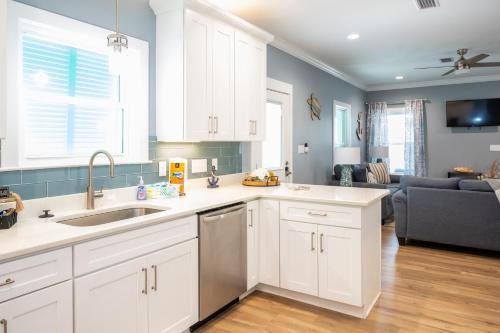 a kitchen with white cabinets and a living room at Cottage Beach House Steps From Beach 3 bedroom 2 bath in Gulf Shores