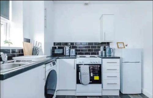 a white kitchen with a dishwasher and a sink at St Helens - Cosy 1 Bed in Saint Helens