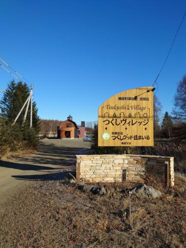 um sinal para uma igreja com um moinho de vento ao fundo em Tsukushi Village em Tsurui