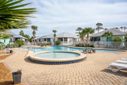 una piscina con mesa, sillas y casas en Cottage Beach House Steps From Beach 3 bedroom 2 bath, en Gulf Shores