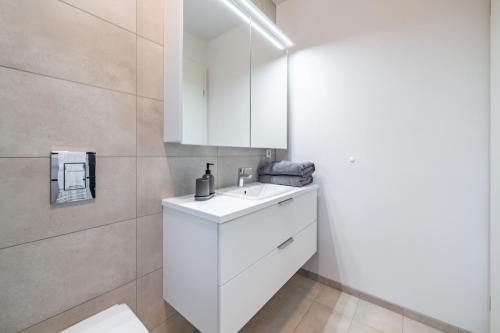 ein Badezimmer mit einem weißen Waschbecken und einem Spiegel in der Unterkunft Glacial Properties, Cozy apartment in Kópavogur in Reykjavík