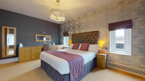 a large bedroom with a large bed and windows at Stirk House Hotel in Clitheroe